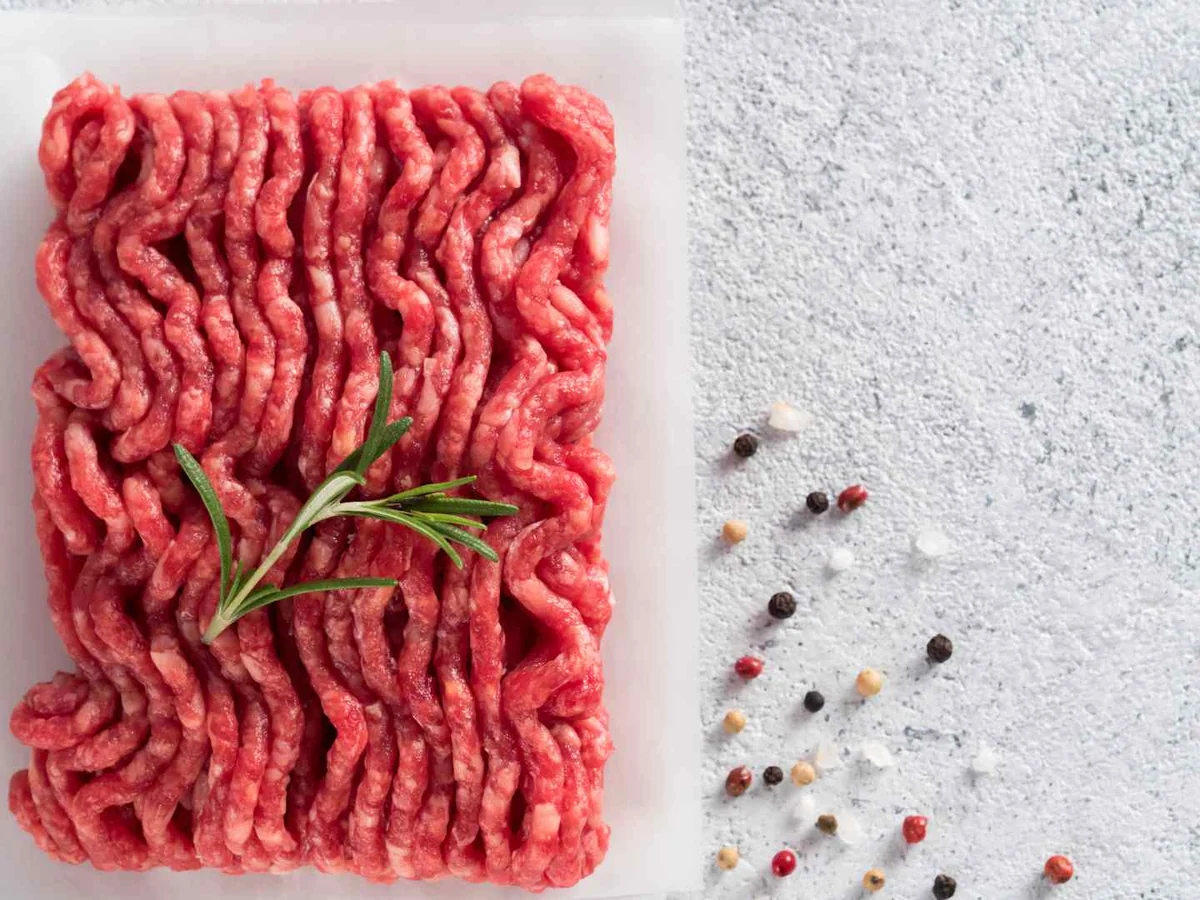 A rectangular block of raw ground beef with rosemary