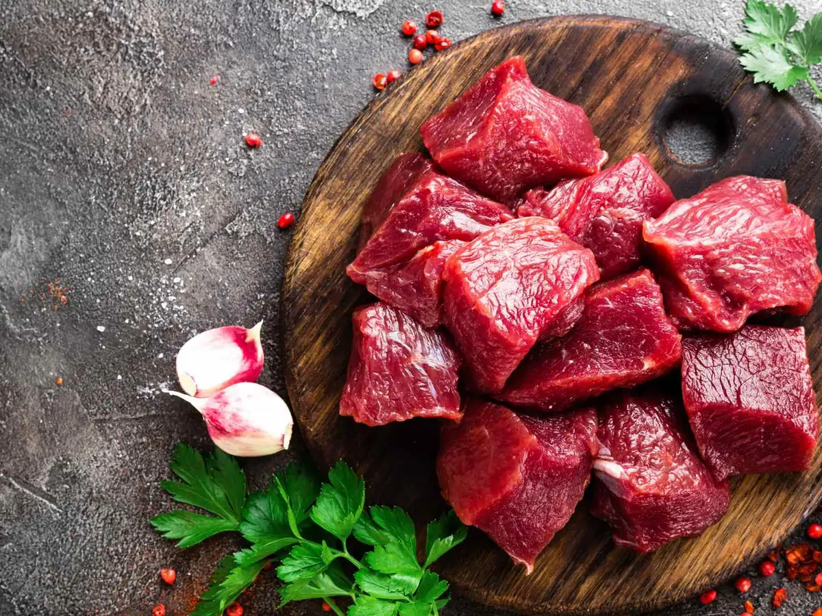 Raw beef chunks on a dark cutting board