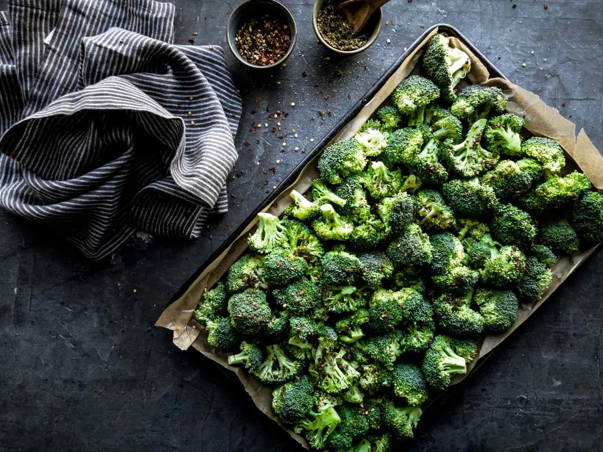 Chopped broccoli florets in a white bowl on a wooden table.