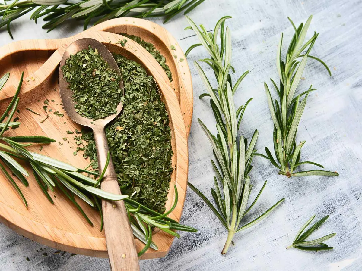 Fresh and dried rosemary arranged in wooden bowls and spoons