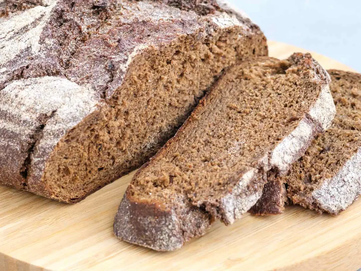 Dark sliced rye loaves and seeds arranged on black boards.