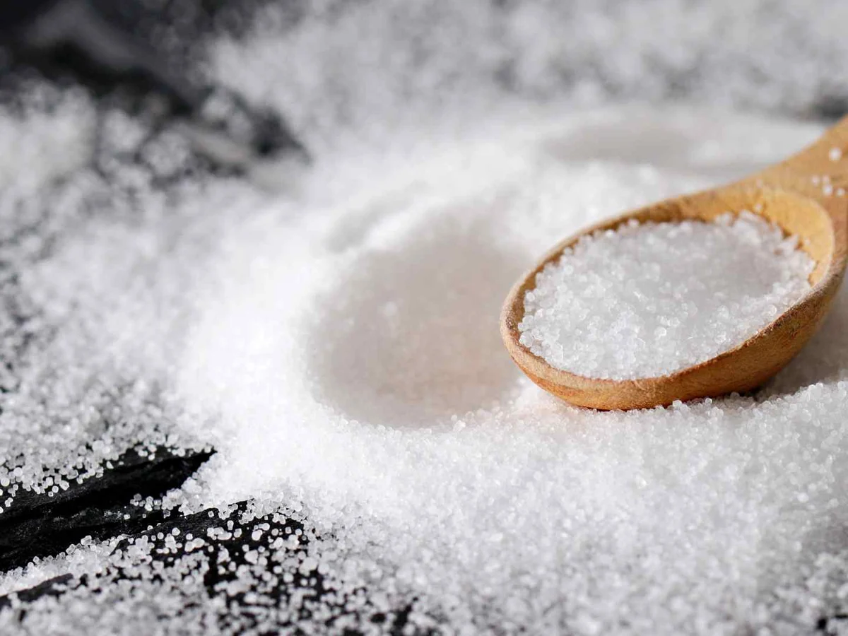 A wooden spoon holding coarse salt over scattered crystals