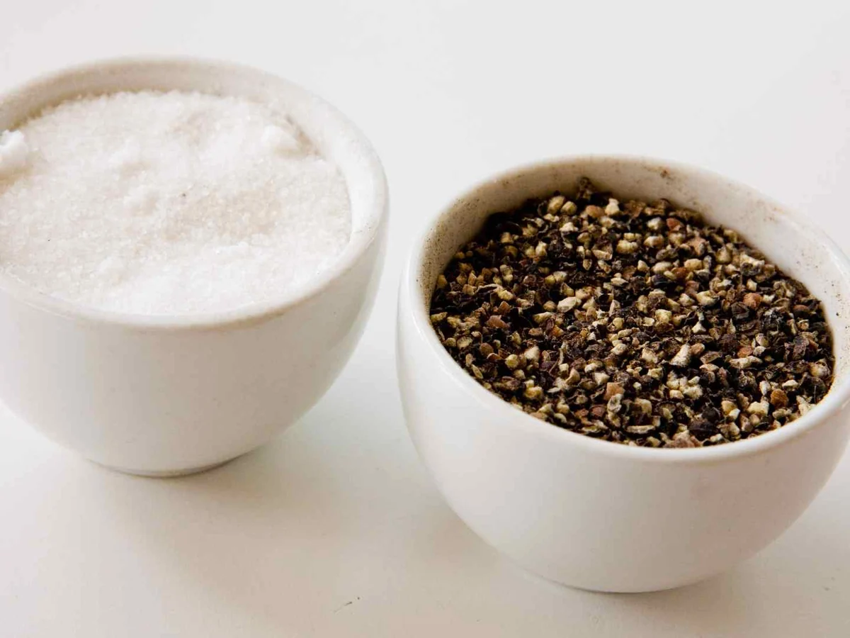 Small white bowls of salt and coarse black pepper