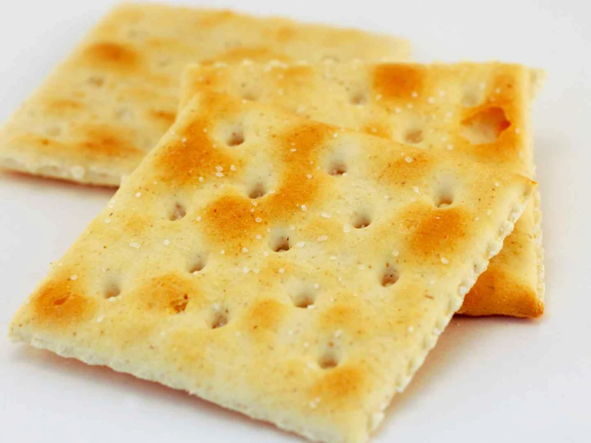 Three square saltine crackers on a white background