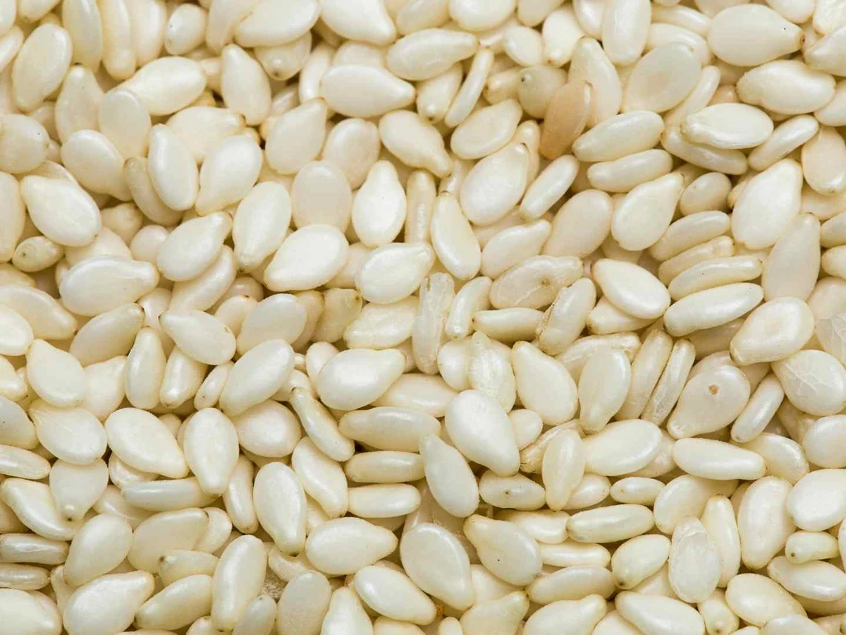 A close-up field of pale sesame seeds filling the frame.