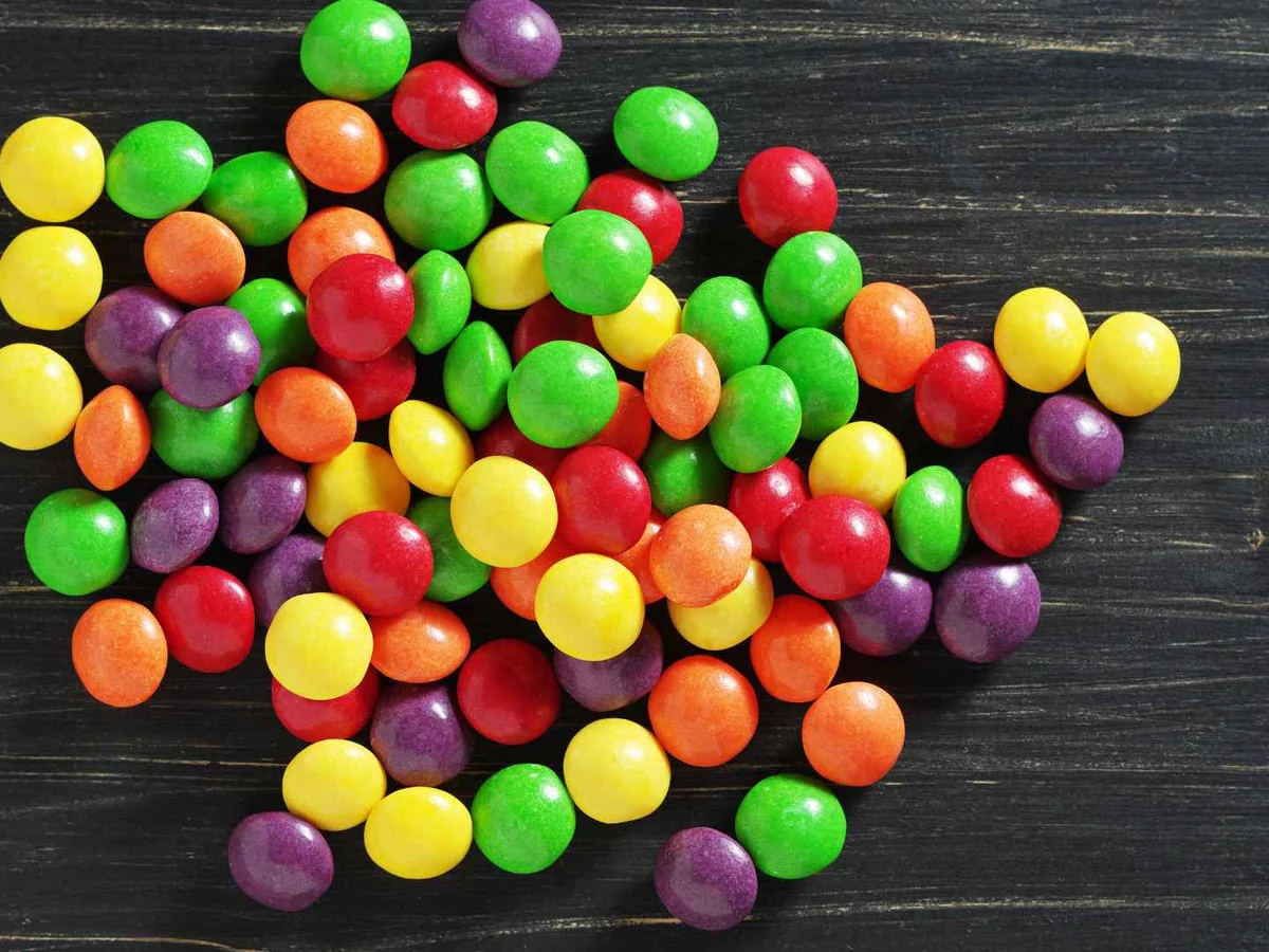 Colorful candy pieces arranged in a heart on dark wood