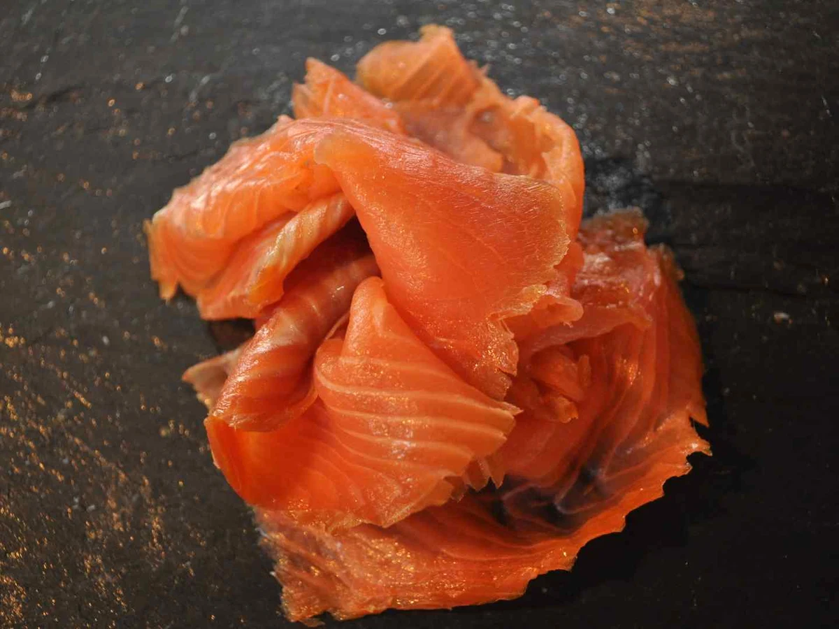 Folded smoked salmon slices on a dark slate surface.