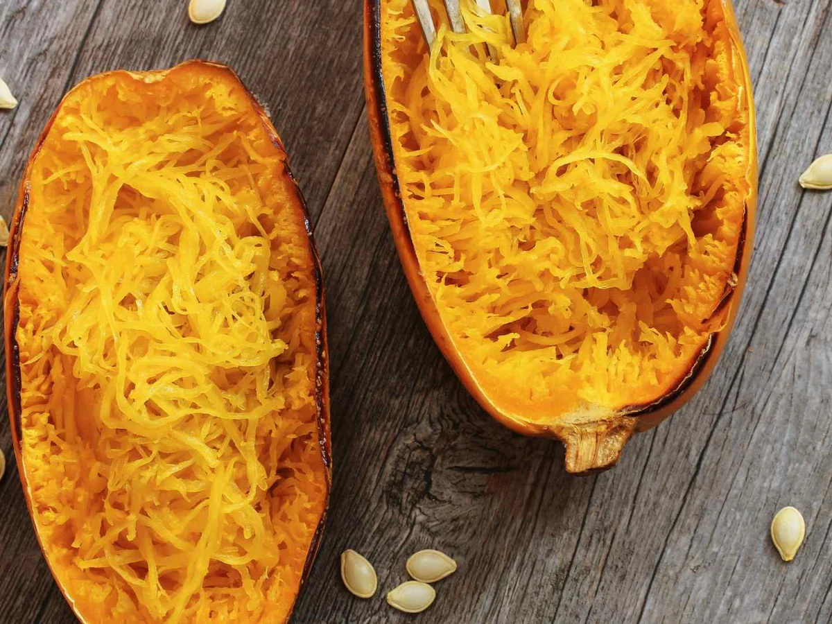Two halved cooked spaghetti squash with loose strands