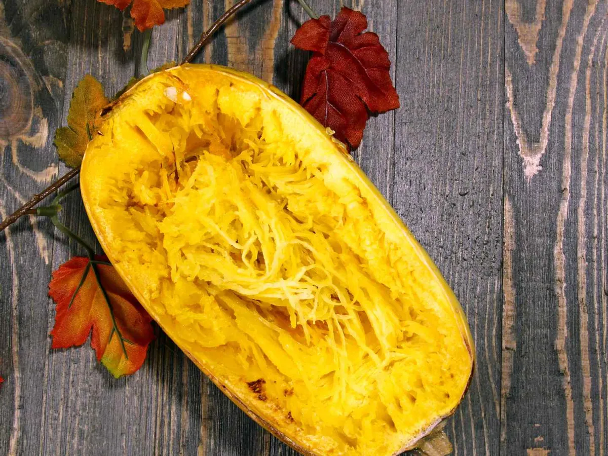 A halved cooked spaghetti squash on a dark autumn table