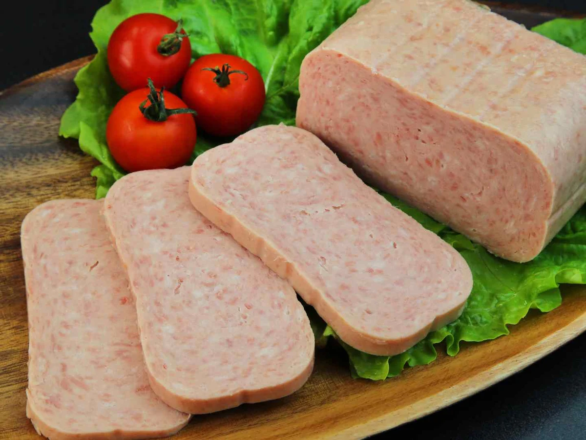Slices of pale pink canned luncheon meat on lettuce with tomatoes.