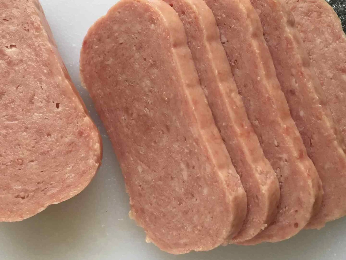 Thick slices of pale pink canned luncheon meat viewed close up.