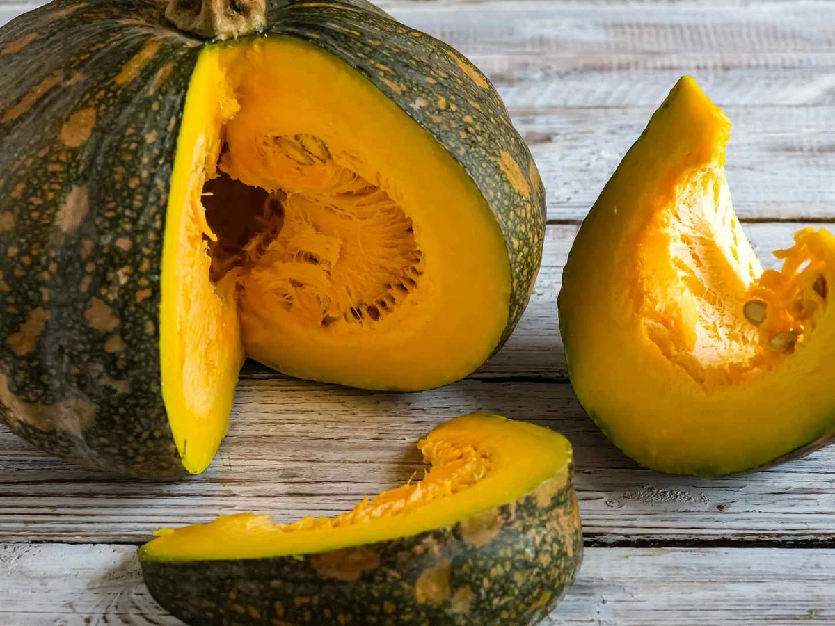 Cut green squash wedges and a halved squash on wood
