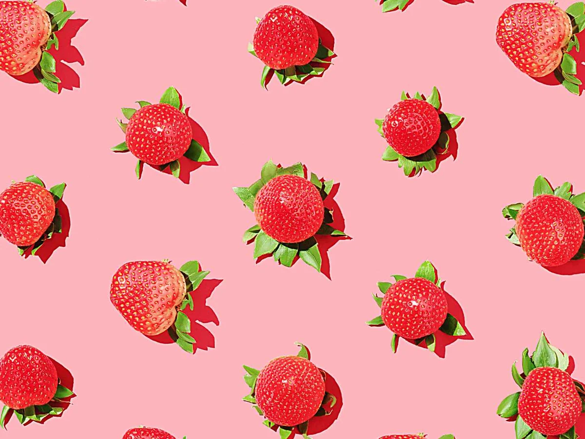 A repeating pattern of illustrated strawberries on a pink background