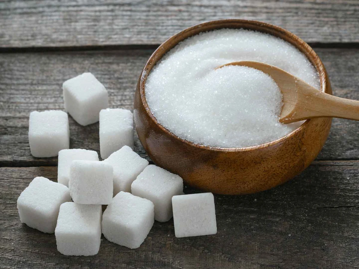 White sugar cubes around a bowl of granulated sugar