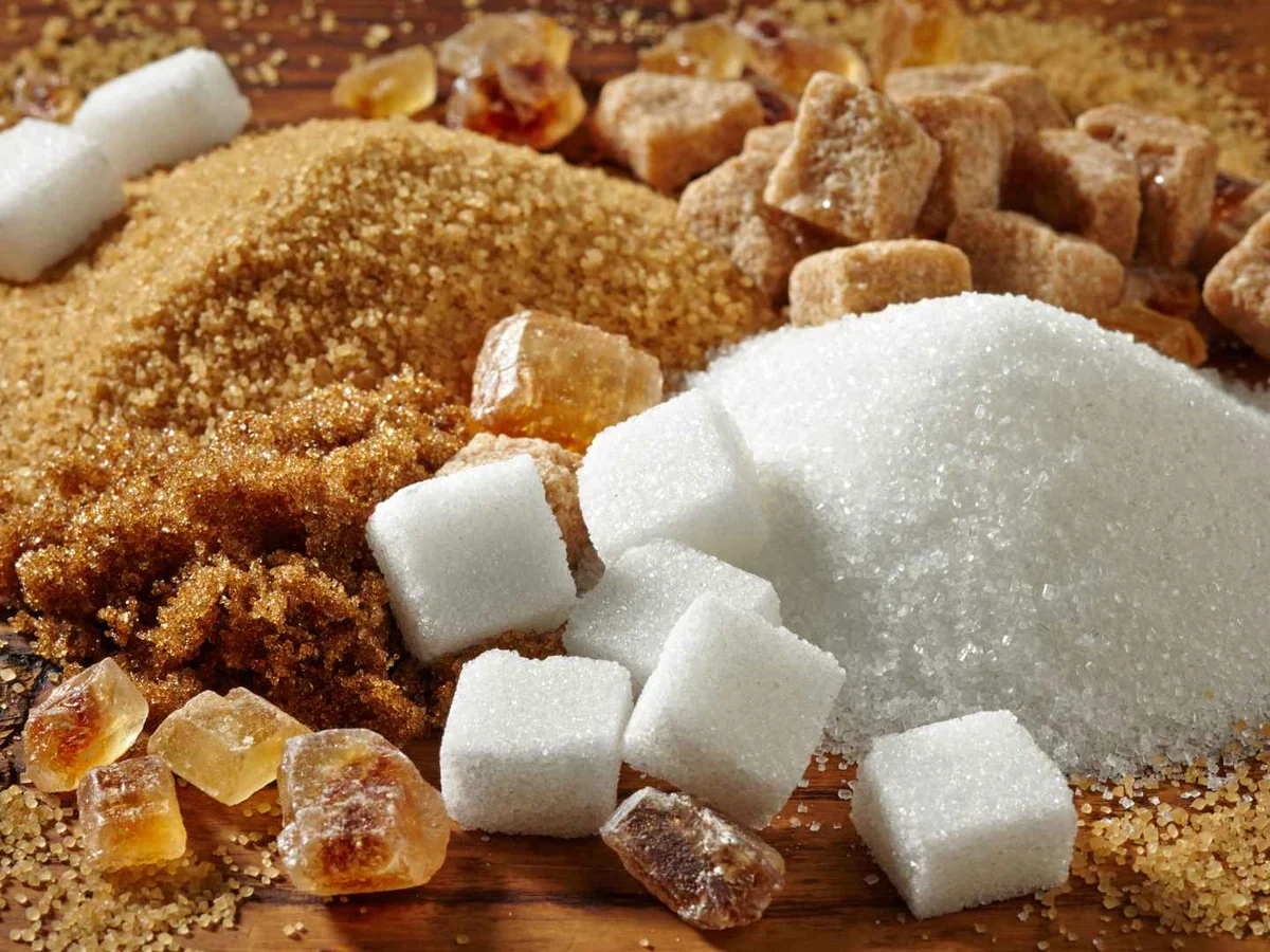 White and brown sugars with sugar cubes on a wooden surface
