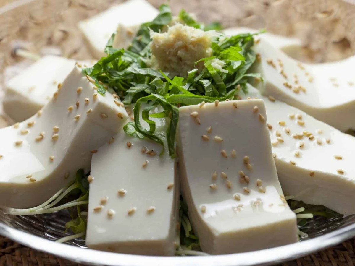 White tofu cubes garnished with herbs and sesame seeds on a plate.