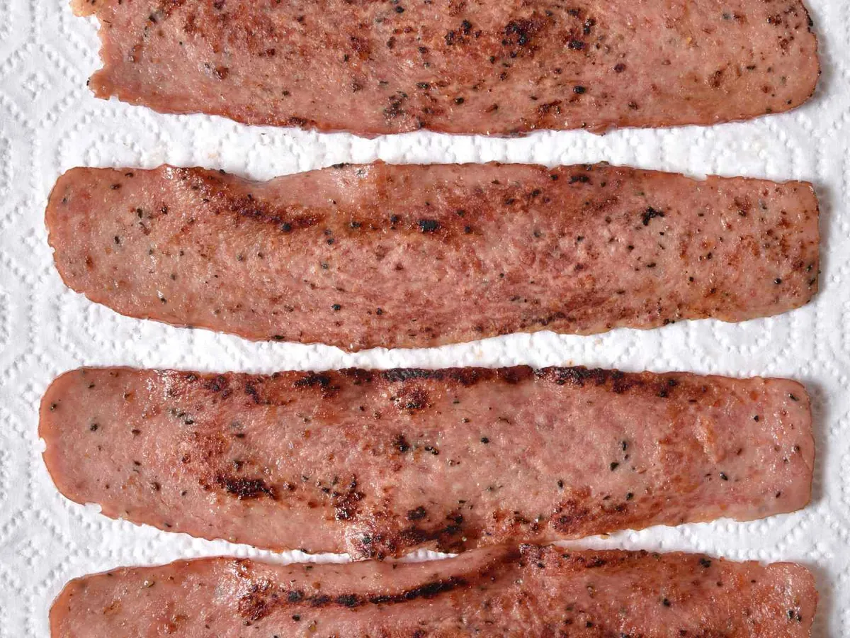Cooked turkey bacon strips draining on a paper towel