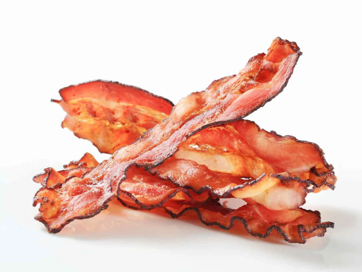 A small pile of crisp bacon strips isolated on white