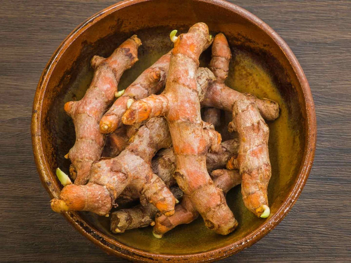 Fresh turmeric roots in a wooden bowl