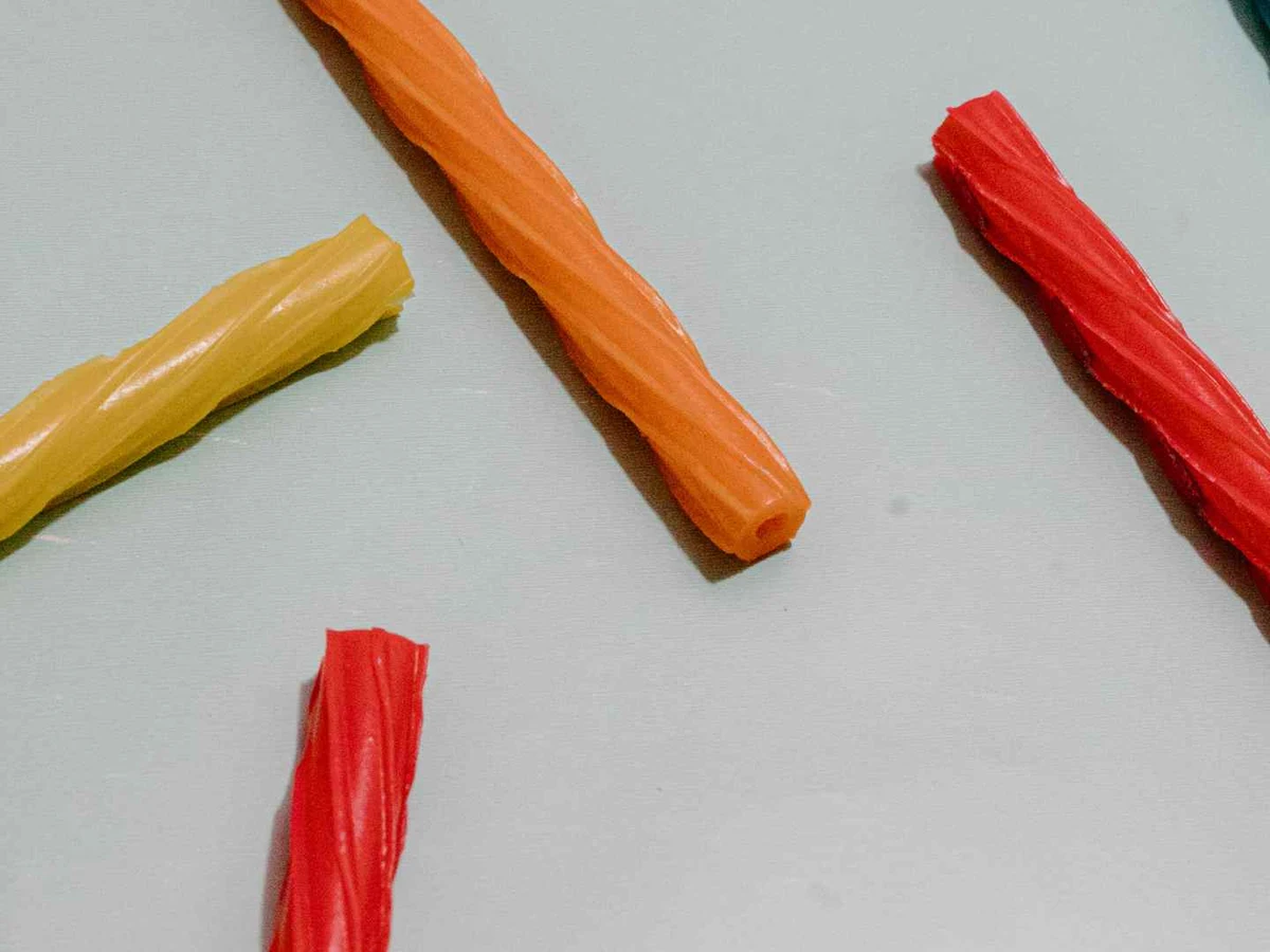 Red, orange, yellow, and blue licorice sticks scattered on gray.