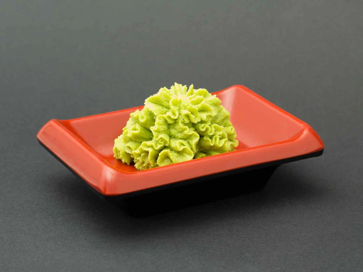 A small mound of green wasabi paste on a red dish