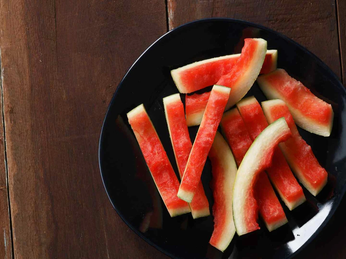 Watermelon rind cut into narrow sticks on a black plate.