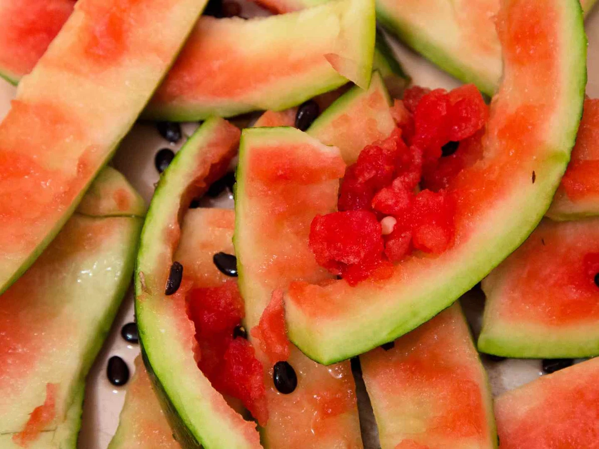 Mixed watermelon rind pieces with some red flesh and black seeds.