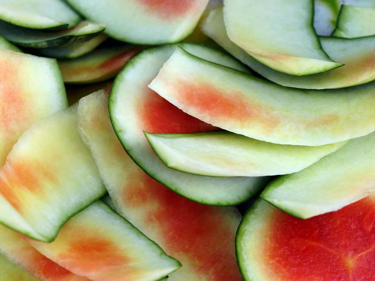 Thin curved watermelon rind pieces piled together in close-up.