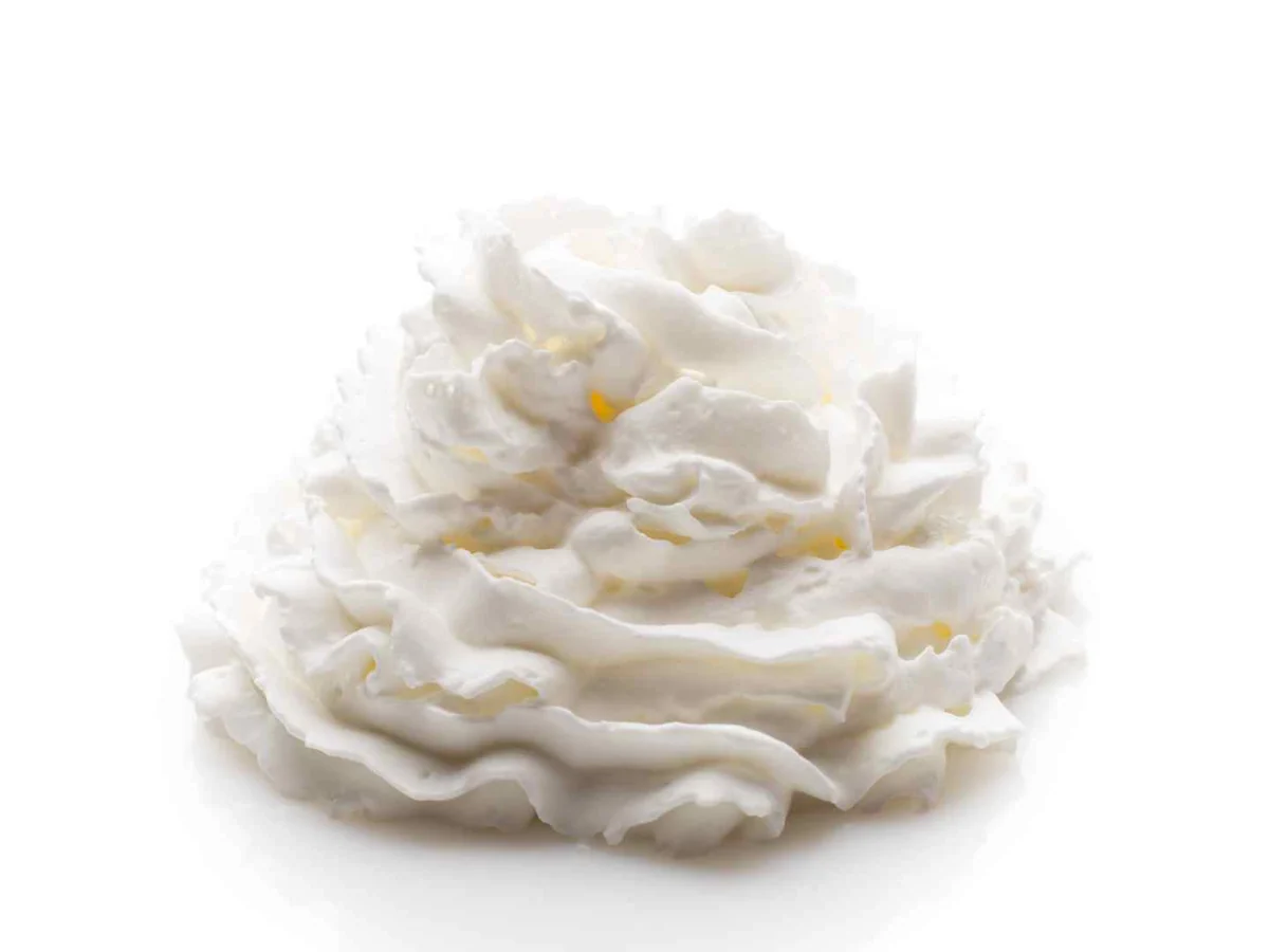 A piped mound of white whipped cream isolated on a white background