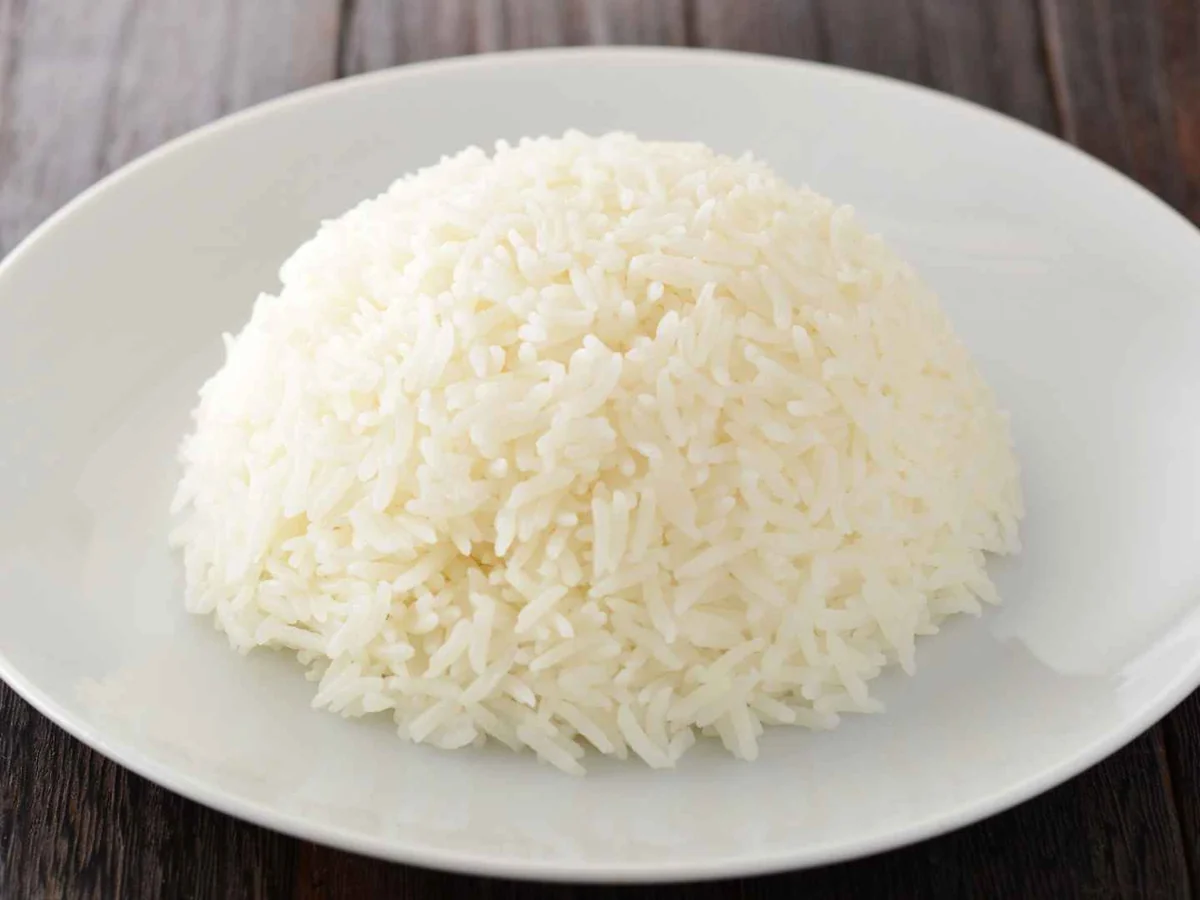 A mound of cooked white rice on a white plate