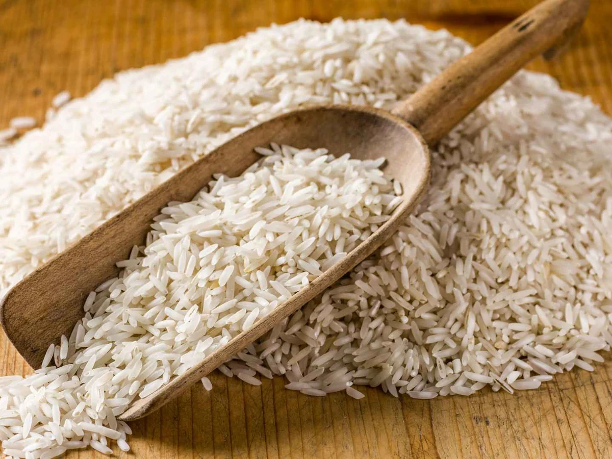 Uncooked white rice with a wooden scoop