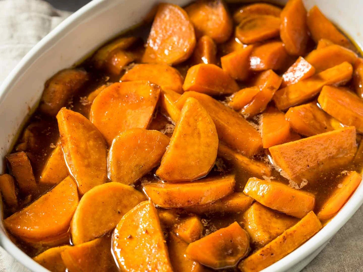Glazed orange yam pieces in a white baking dish.