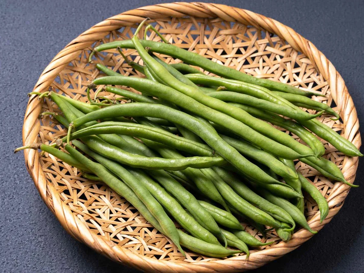 Whole green beans filling a woven round basket