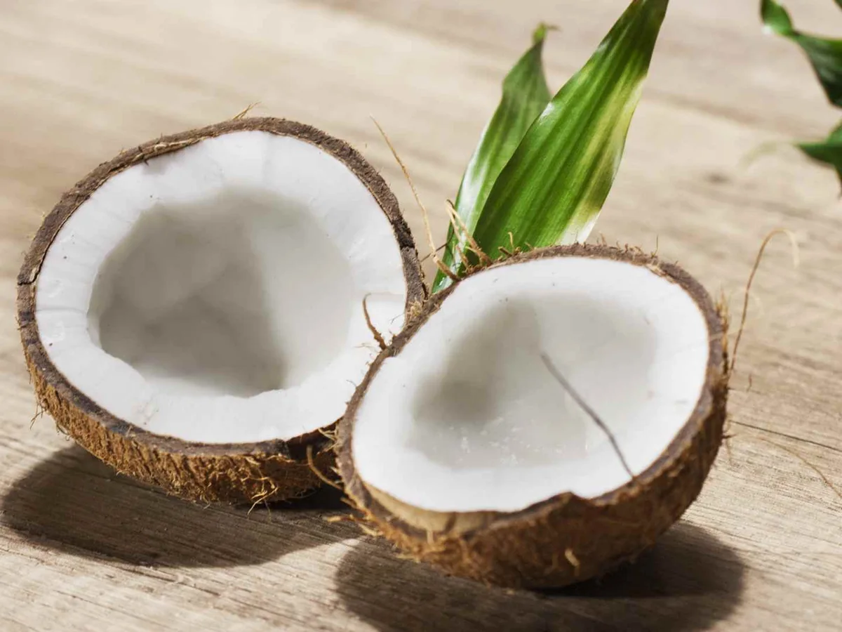 Two coconut halves with white flesh on a wooden table