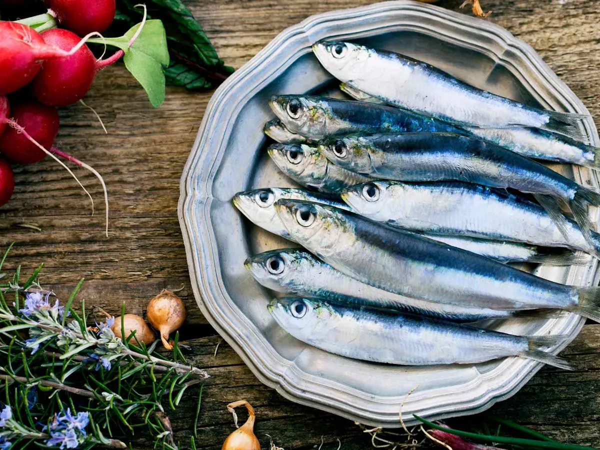 Whole sardines in a metal dish with radishes and herbs