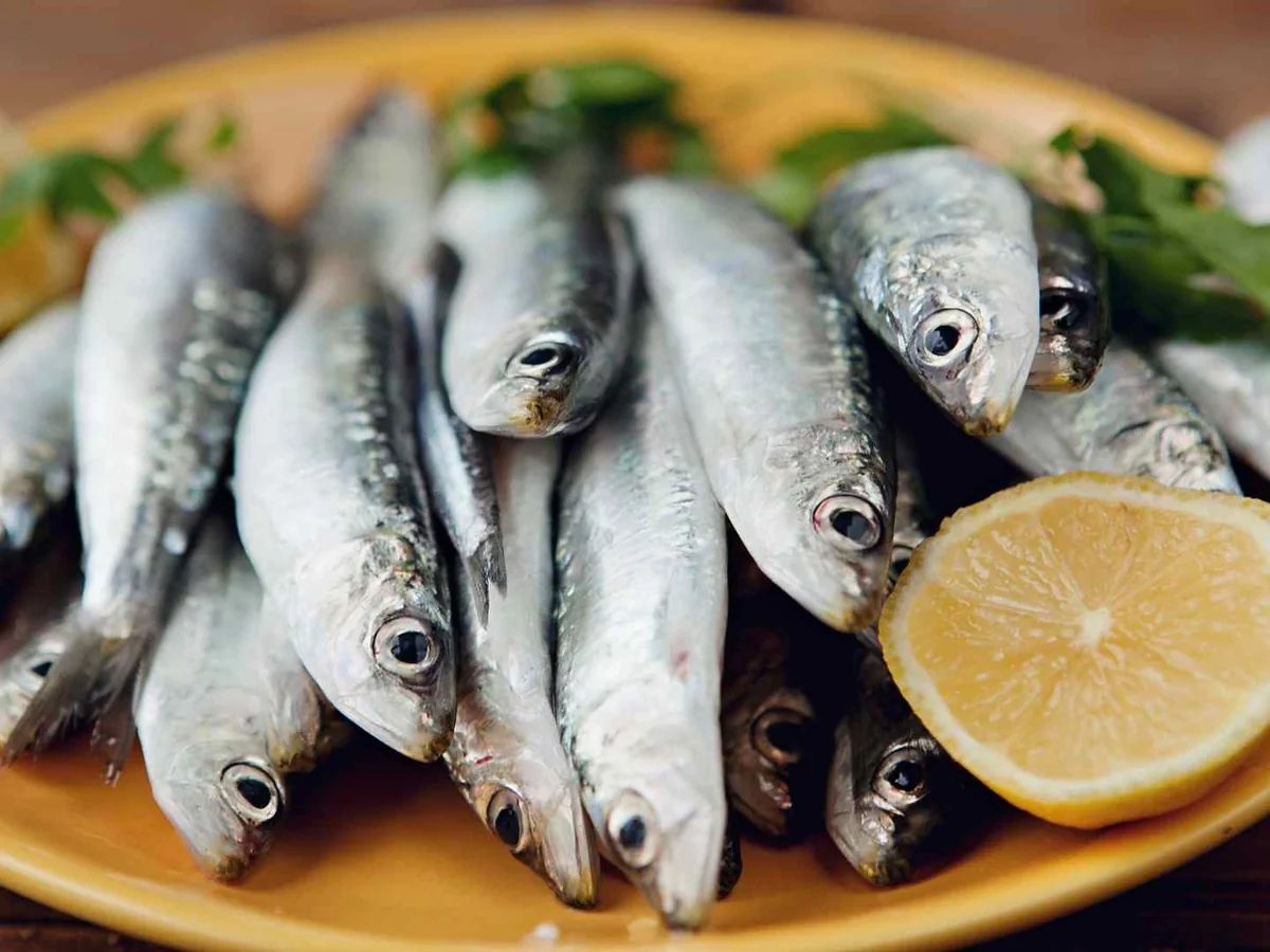 Whole sardines on a plate with a lemon half