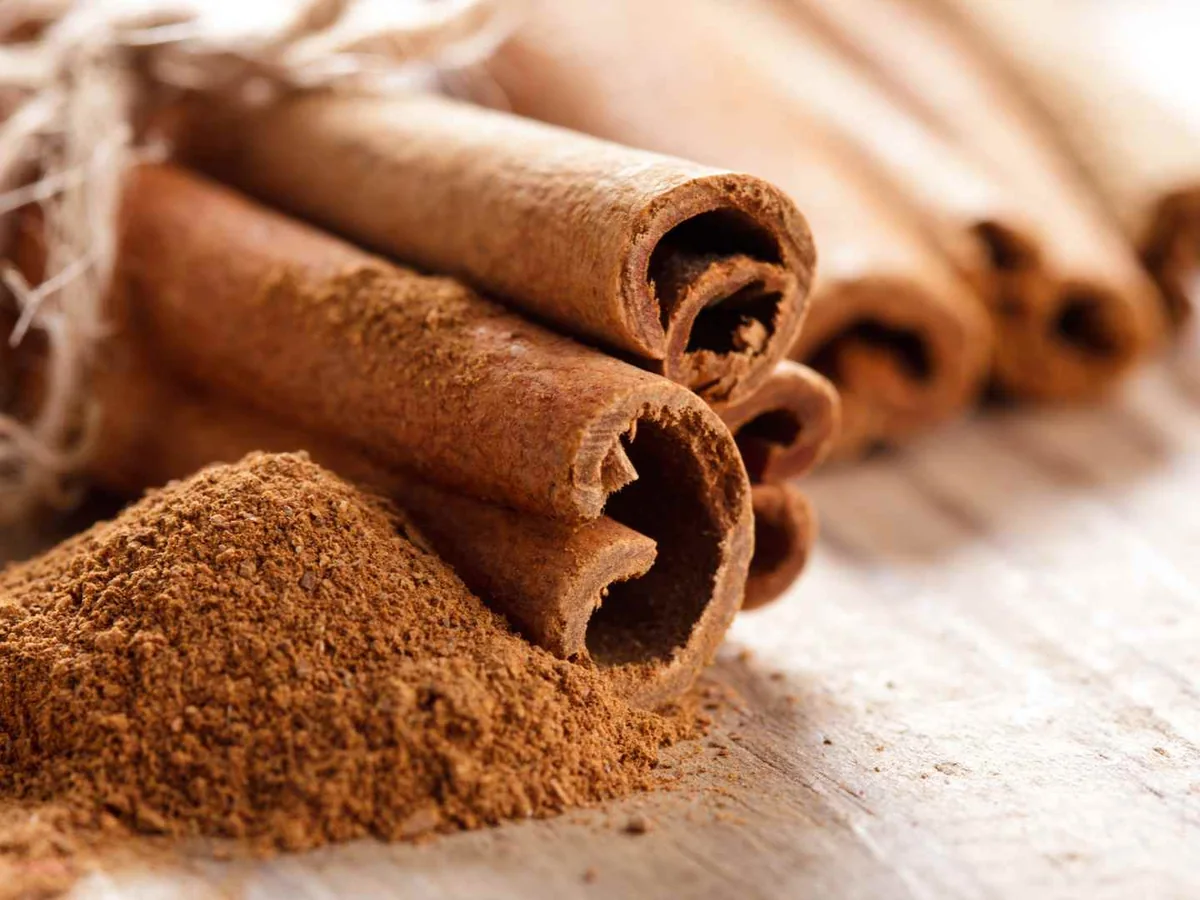 Ground cinnamon beside several cinnamon sticks