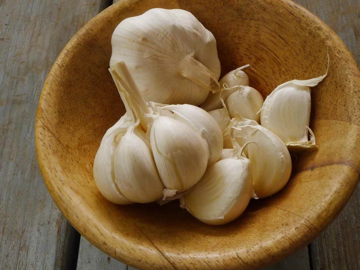 Garlic bulbs and separated cloves in a wooden bowl