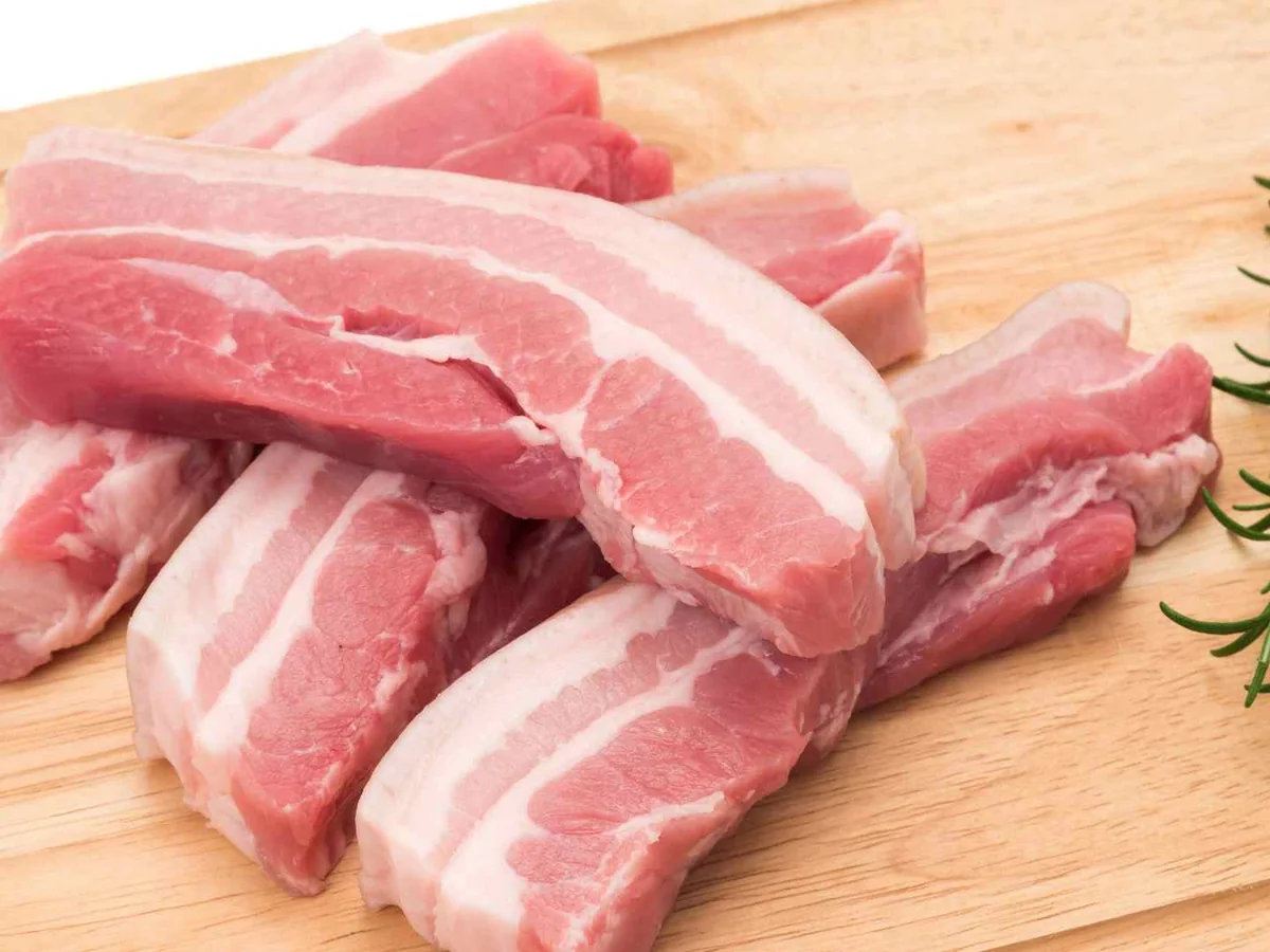 Raw pork belly strips on a wooden cutting board