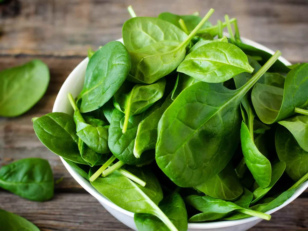 A white bowl filled with baby spinach leaves