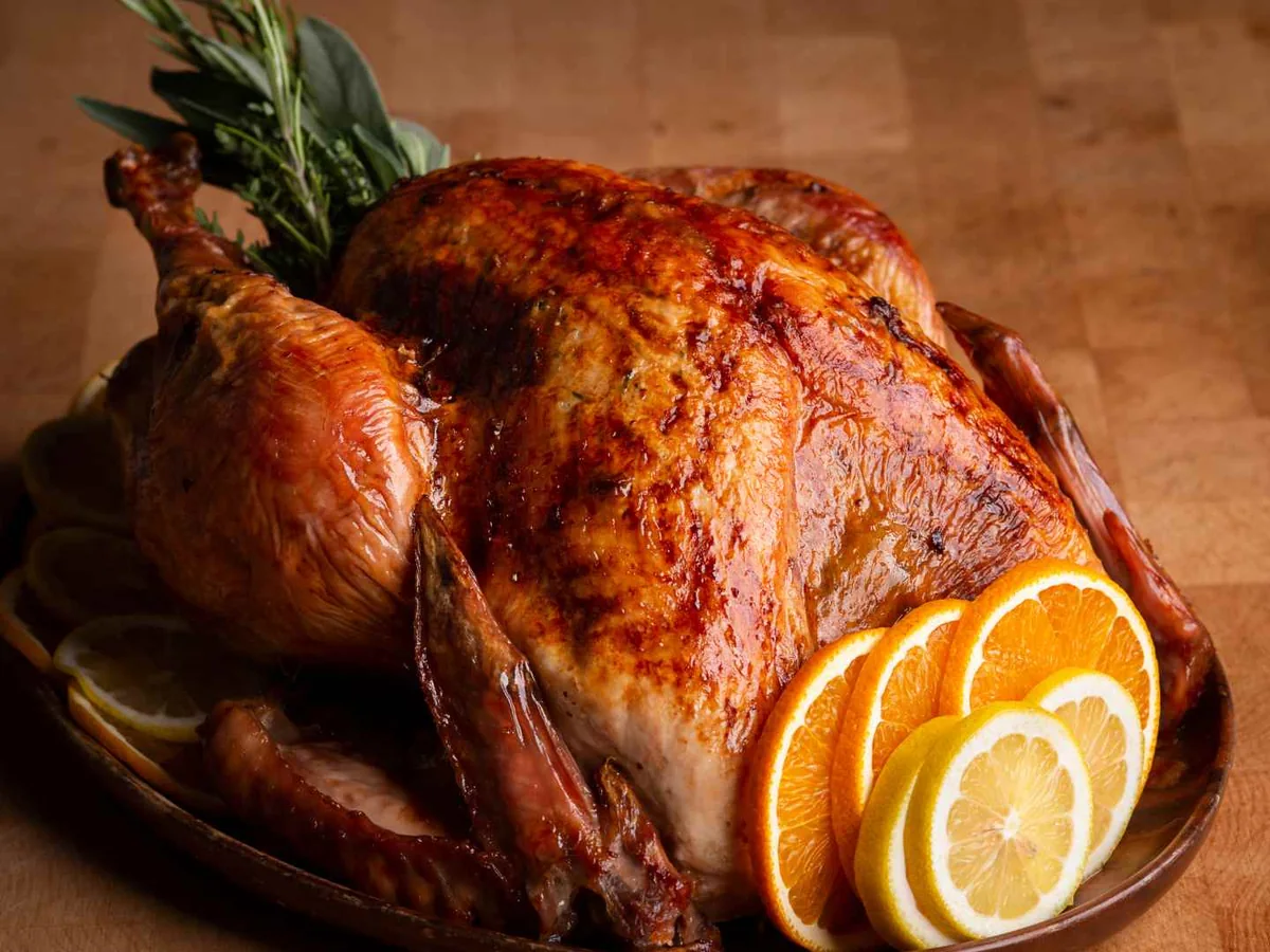 A roasted turkey garnished with rosemary and orange slices