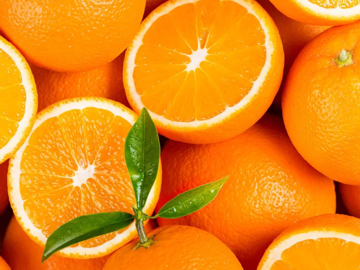 Whole and halved oranges with green leaves