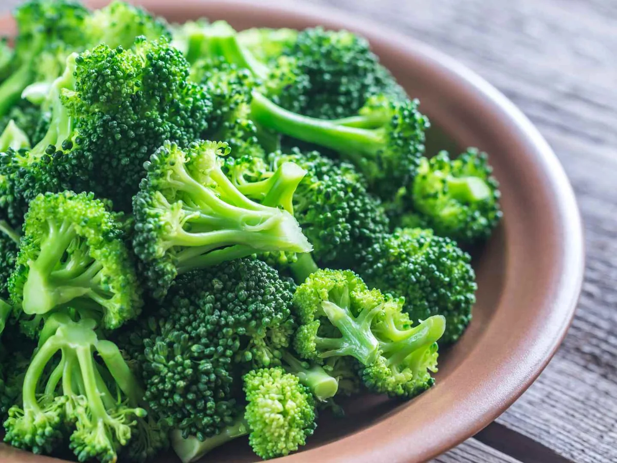 Cooked broccoli florets in a brown bowl