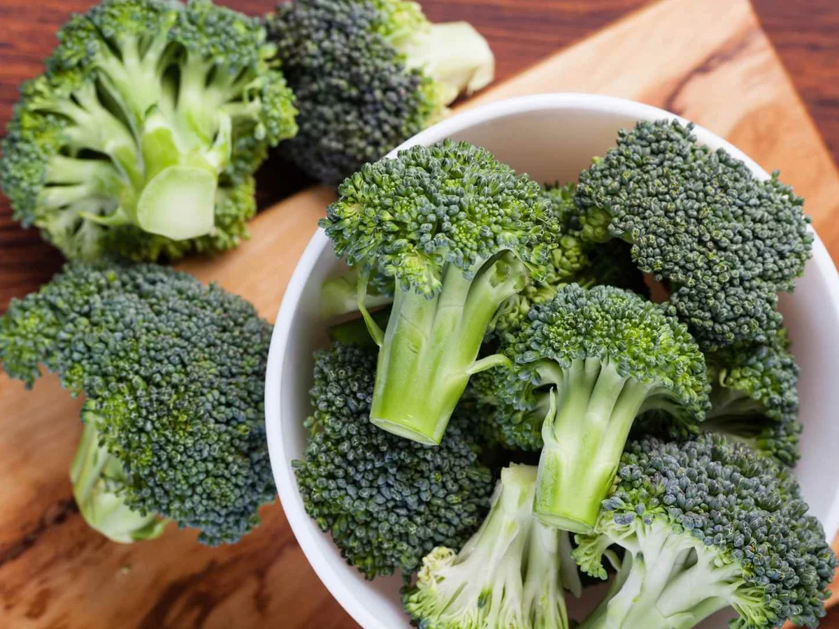 Raw broccoli florets arranged around a small bowl