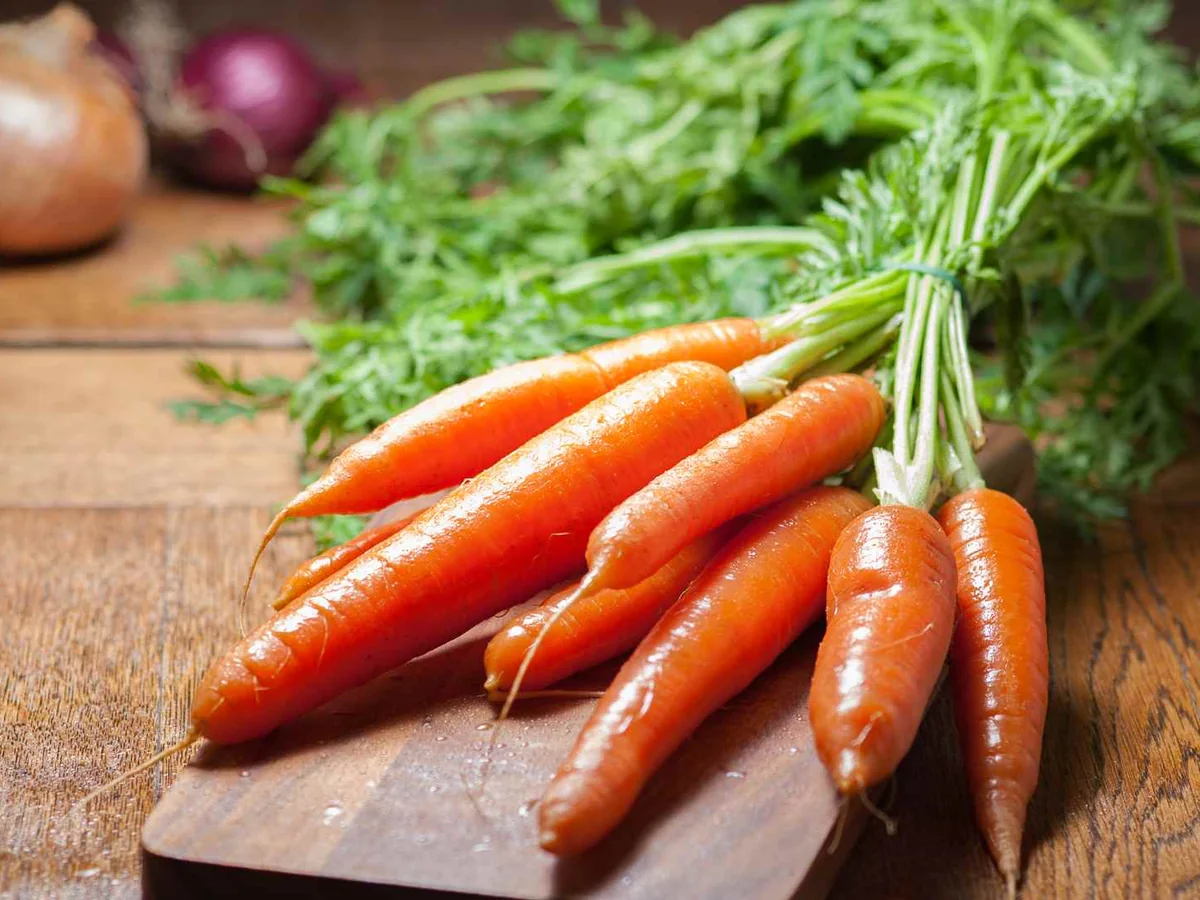 A tied bunch of small carrots on a cutting board