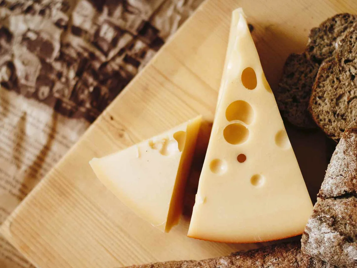 Swiss-style cheese wedges beside slices of dark bread