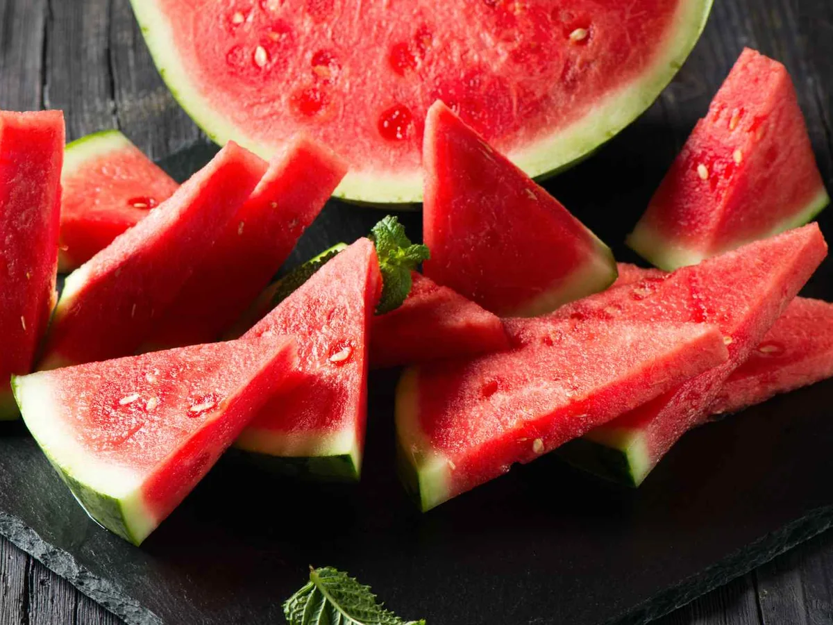 Watermelon wedges and slices on a dark wooden board