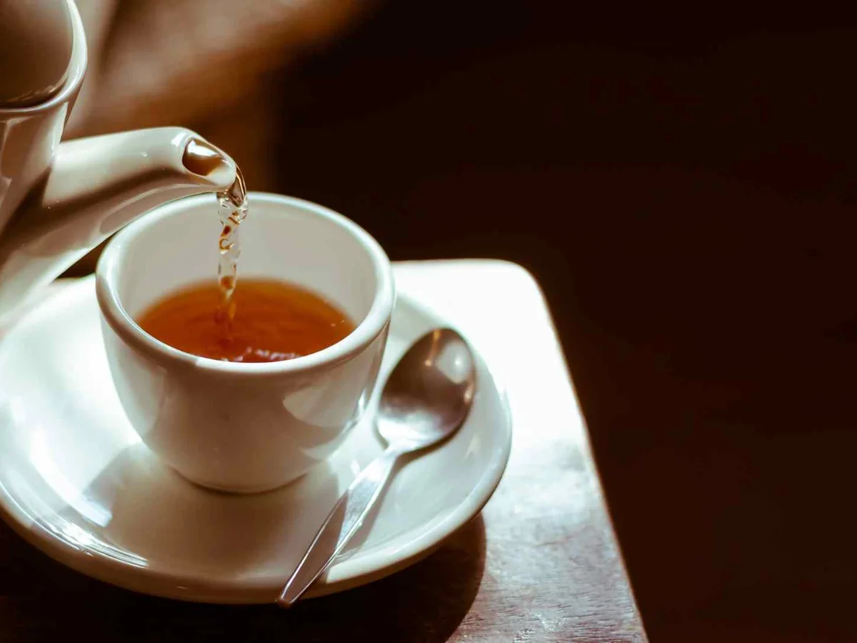 Tea pouring from a white pot into a white cup