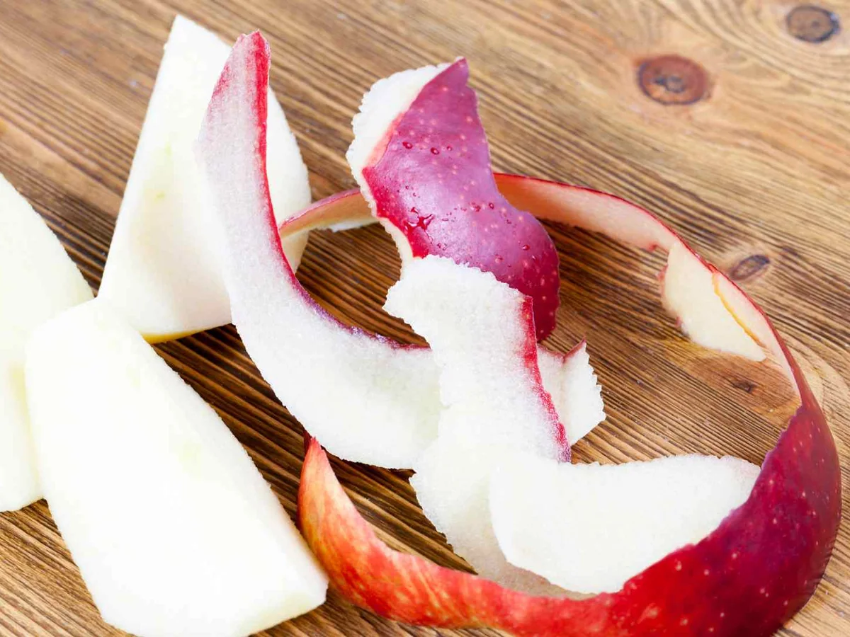 Red apple peels and pale apple pieces on a wooden board