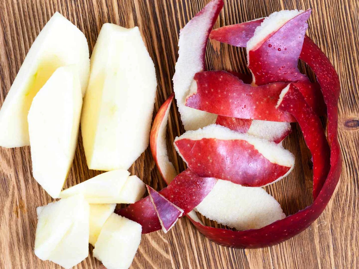 Red apple peel in a bowl beside pale apple chunks